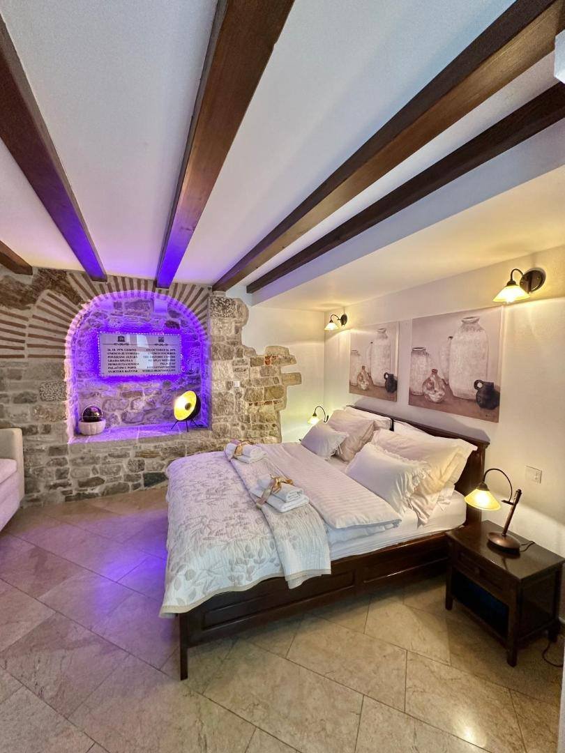 Room with exposed wooden beams, a stone alcove and a double bed