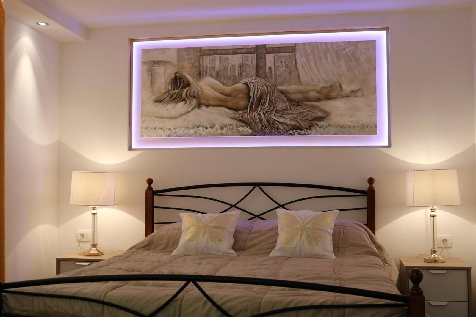 Room with a wrought-iron bed, bedside lamps and a framed picture